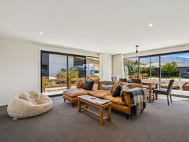 A living room with a sofa and dining area at Dancing Tussock Escape - Cromwell