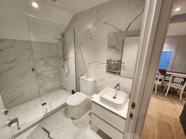 A bathroom with a shower, toilet, sink, and mirror at Studio - Point Wells Holiday Home, Point Wells