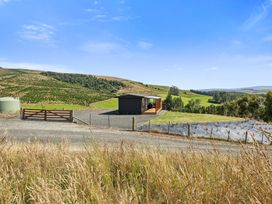 A view of a building with a gate and hills at Limesprings Cottage - Milton