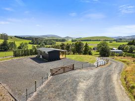 A house with a fenced area and gravel road at Limesprings Cottage - Milton