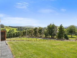 A view of grass and trees with hills in the background at Limesprings Cottage - Milton