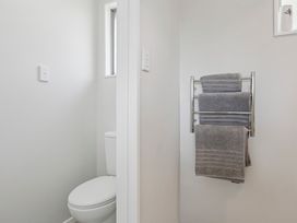 A bathroom with a toilet and towels on a rack at Limesprings Cottage - Milton