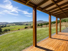 A view from a wooden deck overlooking fields and mountains at Limesprings Cottage - Milton