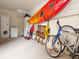 A garage with a kayak, washing machine, dryer and bicycles at Tairua Holiday Home in Tairua