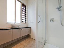 A bathroom with a sink, shower and cabinets at Tairua Holiday Home in Tairua