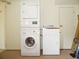 A laundry room with a washing machine and dryer stacked at Tairua Holiday Home in Tairua