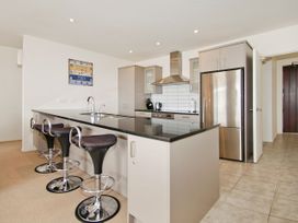 A kitchen with stools and stainless steel appliances at Tairua Holiday Home in Tairua