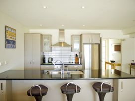 A kitchen with cabinets and bar stools at Tairua Holiday Home in Tairua