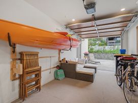 A garage with a kayak on the wall and a bicycle next to a couch at Waterfront Bliss - Tairua Holiday Home, Tairua