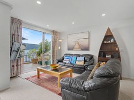 A living room with a sofa, coffee table, and TV at Waterfront Bliss - Tairua Holiday Home, Tairua