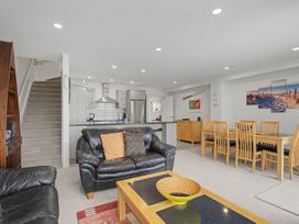 A living room with a sofa and dining table at Waterfront Bliss - Tairua Holiday Home Tairua