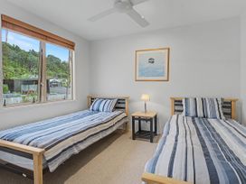 A bedroom with two single beds and a lamp at Waterfront Bliss - Tairua Holiday Home