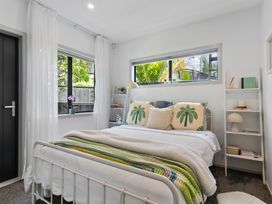 A bedroom with a bed, shelves, and windows at The Bridge Bird Sanctuary - Auckland
