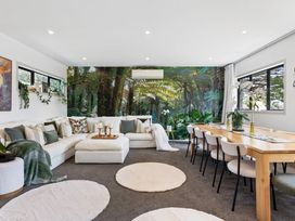 A living room with a sofa and dining area at The Bridge Bird Sanctuary - Auckland Holiday Home Auckland