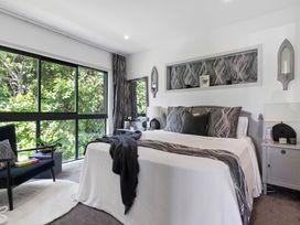 A bedroom with a bed and chair at The Bridge Bird Sanctuary - Auckland