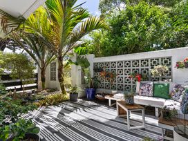 An outdoor seating area with plants and decorative wall at The Bridge Bird Sanctuary - Auckland