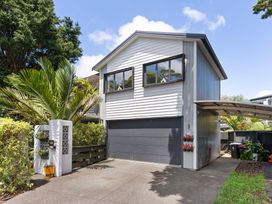 A house with a garage and palm tree at The Bridge Bird Sanctuary - Auckland