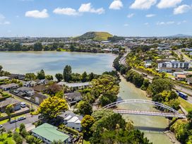 A landscape with a bridge over a lake and houses at The Bridge Bird Sanctuary - Auckland