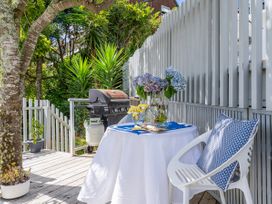An outdoor area with a table, flowers, a barbecue grill, and a chair at Panoramic Views on Paku - Tairua