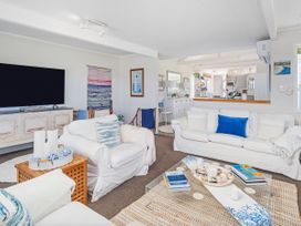 A living room with a television and sofa at Panoramic Views on Paku - Tairua Family Retreat