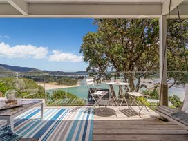 An outdoor area with a table and chairs overlooking a scenic view at Panoramic Views on Paku - Tairua