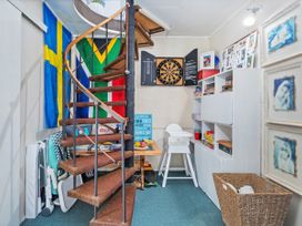 A room with a spiral staircase and shelves at Panoramic Views on Paku - Tairua
