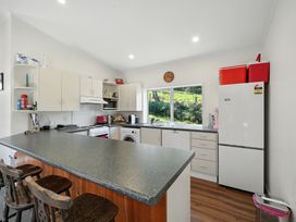 A kitchen with counter, refrigerator and oven at Maison Pierre Rouge - Duvauchelle Holiday Home Akaroa