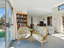 A living room with armchairs and a bookshelf at Maison Pierre Rouge - Duvauchelle Holiday Home Akaroa