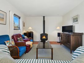 A living room with a fireplace and television at Maison Pierre Rouge - Duvauchelle Holiday Home, Akaroa