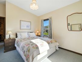 A bedroom with a bed and nightstand at Maison Pierre Rouge - Duvauchelle Holiday Home Akaroa