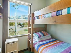 A bedroom with a bunk bed and nightstand at Maison Pierre Rouge - Duvauchelle Holiday Home, Akaroa