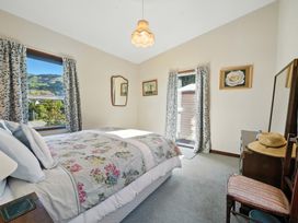 A bedroom with a bed and bedside table at Maison Pierre Rouge - Duvauchelle Holiday Home Akaroa