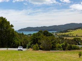 A view of trees and ocean with hills in the background at Coopers Beach