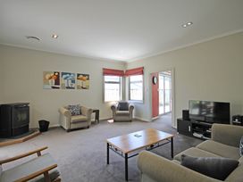 A living room with a sofa, armchair, and television at Relax on Richmond - Taranaki Holiday Home, New Plymouth