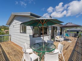 A deck with a table and chairs at Whangapoua