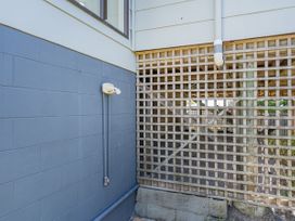 An outdoor area with a wall and a lattice structure at Whangapoua