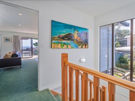 A hallway with a painting and stairs at Whangapoua