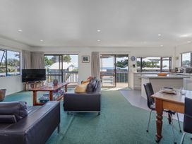 A living room with a television, sofa and dining table at Whangapoua