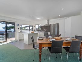 A kitchen with a dining table and chairs at Whangapoua in Whangapoua