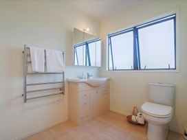 A bathroom with a sink, mirror and toilet at Whangapoua