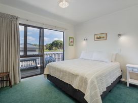 A bedroom with a bed and a window leading to a balcony at Whangapoua