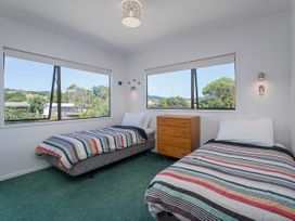 A bedroom with two beds and a chest of drawers at Whangapoua