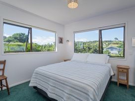 A bedroom with a bed and windows at Whangapoua