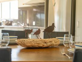 A dining room table with a wooden sculpture and tableware at Whangapoua