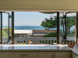A kitchen with window view of ocean and trees at Whangapoua