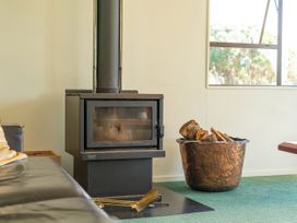 A wood stove with firewood in a bowl at Whangapoua