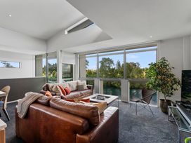 A living room with a sofa, coffee table, and large windows at Lake Taupo Holiday Home in Taupo