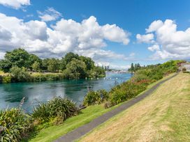 A river with grassy banks and trees at Lake Taupo Holiday Home in Taupo