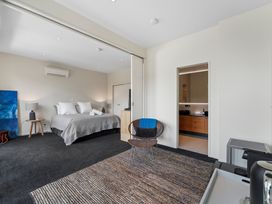 A bedroom with a bed and a chair at Lake Taupo Holiday Home in Taupo