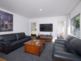 A living room with a sofa and television at The Bach - Kaikoura Holiday Home in Kaikoura